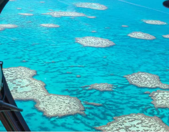 Coral reefs of the Great Barrier Reef in turquoise water, seen through a helicopter window