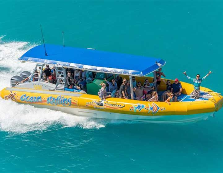 Yellow Ocean Rafting boat full of passengers speeding across turquoise water in the Whitsunday Islands