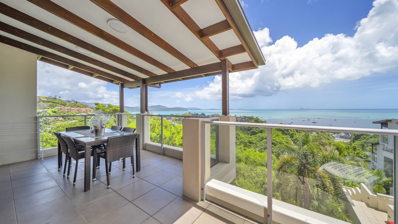 Covered terrace with outdoor dining setting looking over Pioneer Bay to the Coral Sea and Whitsunday Islands, 1 bedroom apartment at Whitsunday Reflections, Airlie Beach