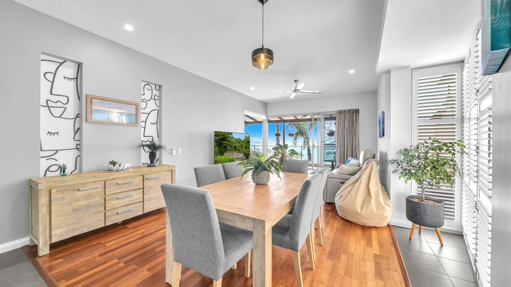 Two bedroom apartment dining table and living room with balcony and ocean view at Whitsunday Reflections, Airlie Beach