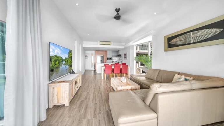 Leather corner lounge and Smart TV looking back to the dining table and kitchen, 2 bedroom apartment at Whitsunday Reflections, Airlie Beach
