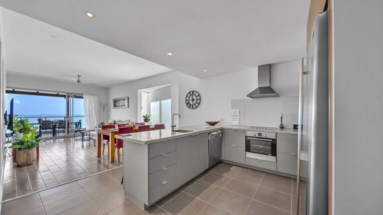 Kitchen with stone benches and Bosch oven opening to the dining, lounge and a balcony over the ocean, 2 bedroom Premium Ocean View apartment at Whitsunday Reflections, Airlie Beach