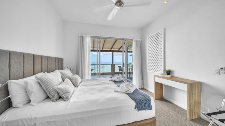 Second bedroom with king bed and sliding doors to a covered balcony over the Coral Sea and Whitsunday Islands, 2 bedroom Premium Ocean View apartment at Whitsunday Reflections, Airlie Beach