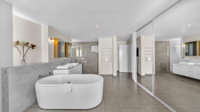 Open-plan main ensuite with freestanding bath, marble half wall, twin basins, screenless shower and mirrored wardrobes, 3 bedroom apartment at Whitsunday Reflections, Airlie Beach
