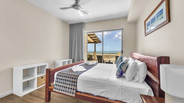 Second bedroom with queen bed and sliding doors to the balcony and a view of the Coral Sea and Whitsunday Islands, 3 bedroom apartment at Whitsunday Reflections, Airlie Beach