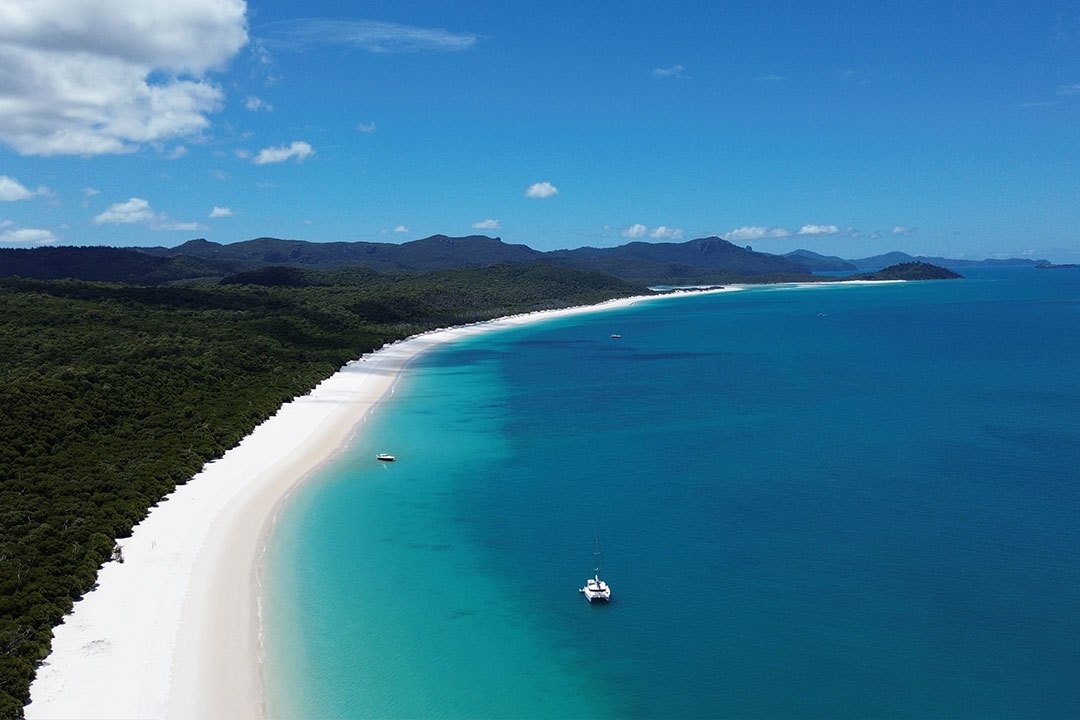 A catamaran and a small boat anchored in turquoise water off Whitehaven Beach, Whitsunday Island
