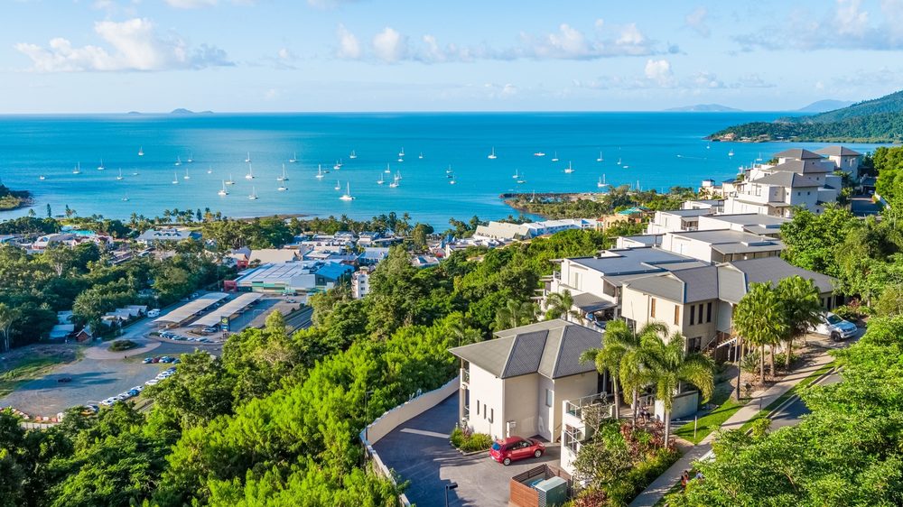Aerial view of the Whitsunday Reflections driveway and car park on the hill above Airlie Beach, with Pioneer Bay and the Whitsunday Islands beyond