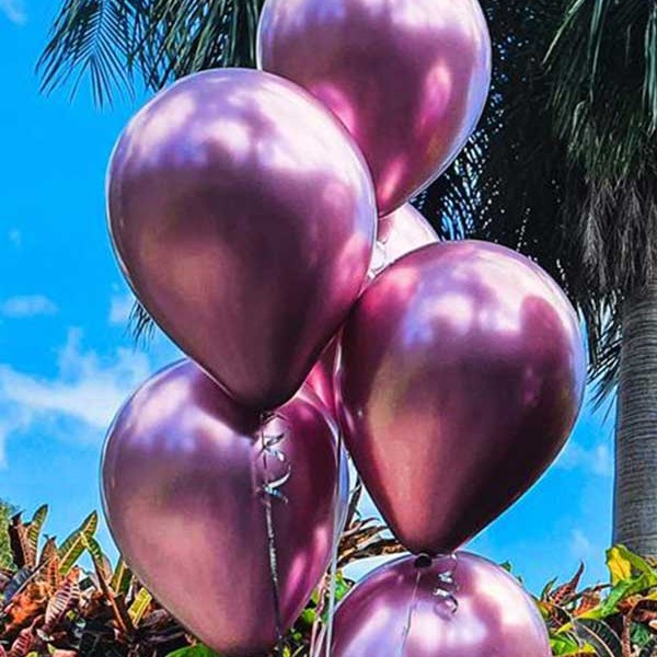 Bundle of five chrome pink latex balloons against palm trees and blue sky, balloons delivered to Whitsunday Reflections, Airlie Beach