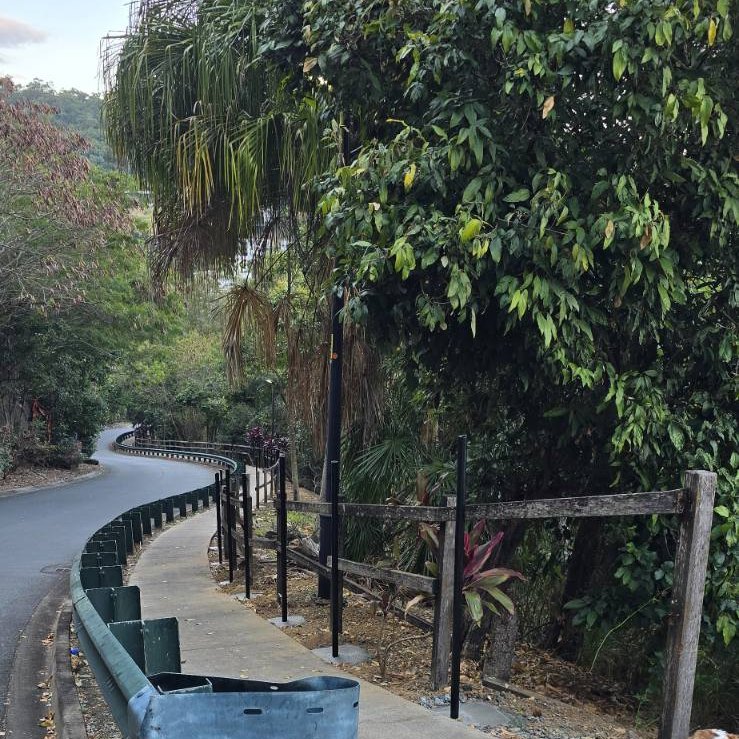 Paved footpath with a safety rail winding down the hill through rainforest from Whitsunday Reflections towards Airlie Beach