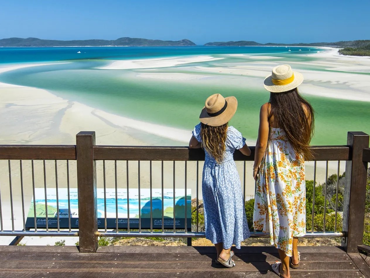 Two visitors at the Hill Inlet lookout on Tongue Point, looking over the swirling white sand and turquoise water of Hill Inlet, Whitsunday Island