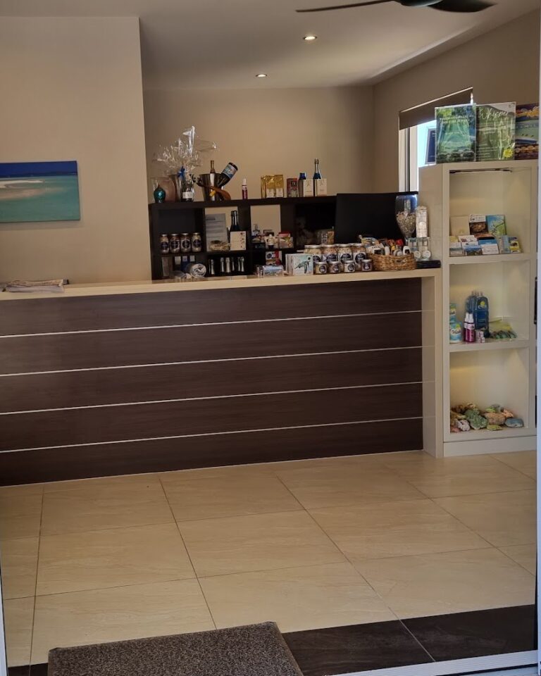 Inside the Whitsunday Reflections reception office, with the front counter, shelves of local produce and gifts, and tour brochures, Airlie Beach
