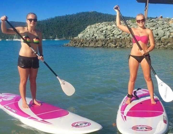 Two paddle boarders standing on their boards in the shallows near the Coral Sea Marina breakwall, Airlie Beach