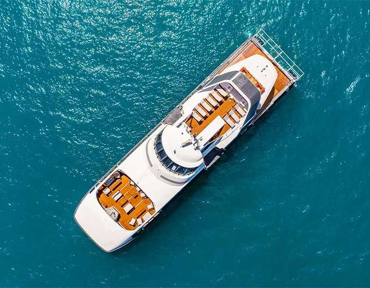 Aerial view of ZigZag Whitsundays' Super Flyer, a white day cruise vessel with timber sun decks, on the water in the Whitsunday Islands